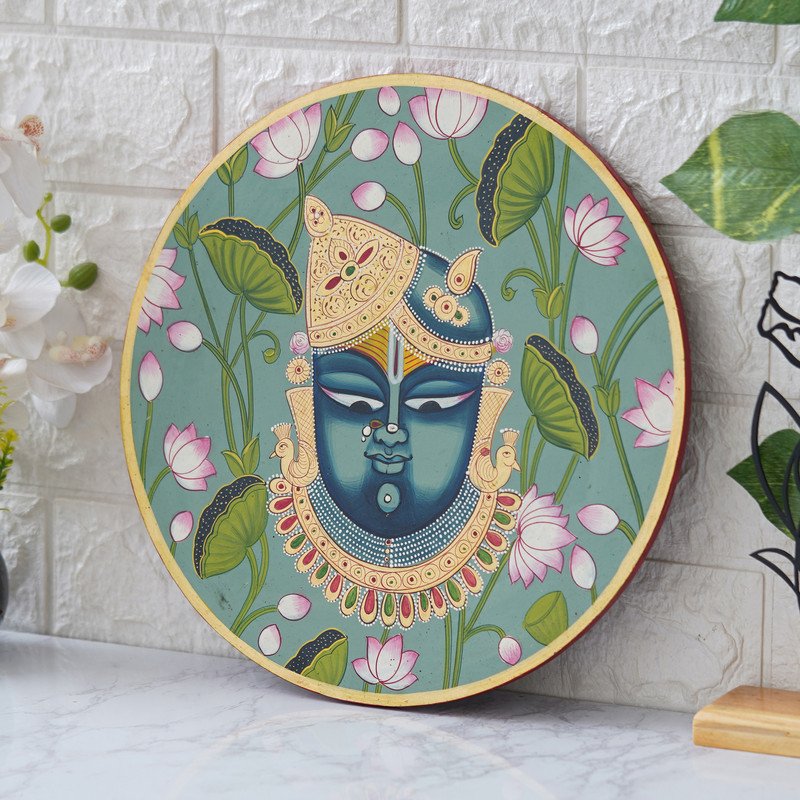 This beautiful pichwai painting depicts Shrinathji, a revered Hindu deity, adorned with flowers and jewels