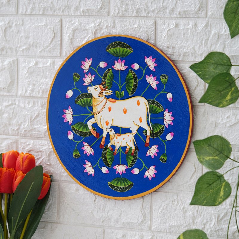 This beautiful pichwai painting features a mother cow and her calf nuzzling each other, surrounded by a vibrant array of flowers.