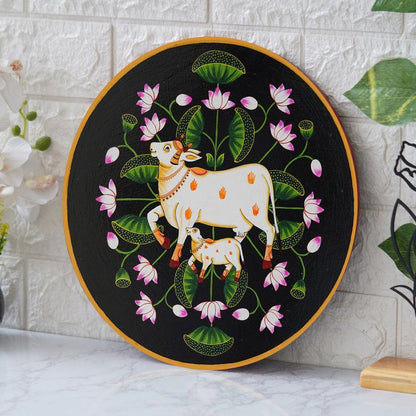 This beautiful pichwai painting features a mother cow and her calf nuzzling each other, surrounded by a vibrant array of flowers.