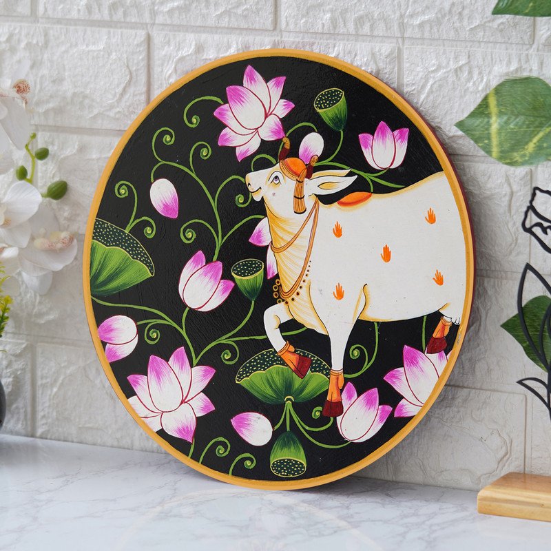 This beautiful pichwai painting features a serene white cow adorned with a vibrant floral headdress.